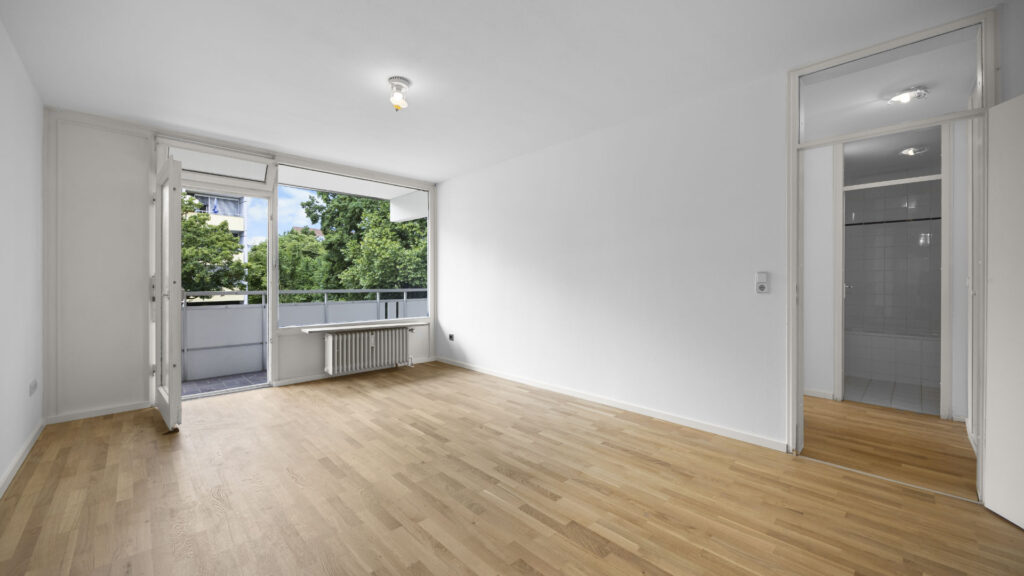 Empty living room with balcony door and wooden floor in Munich-Berg am Laim condominium