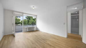 Empty living room with balcony door and wooden floor in Munich-Berg am Laim condominium