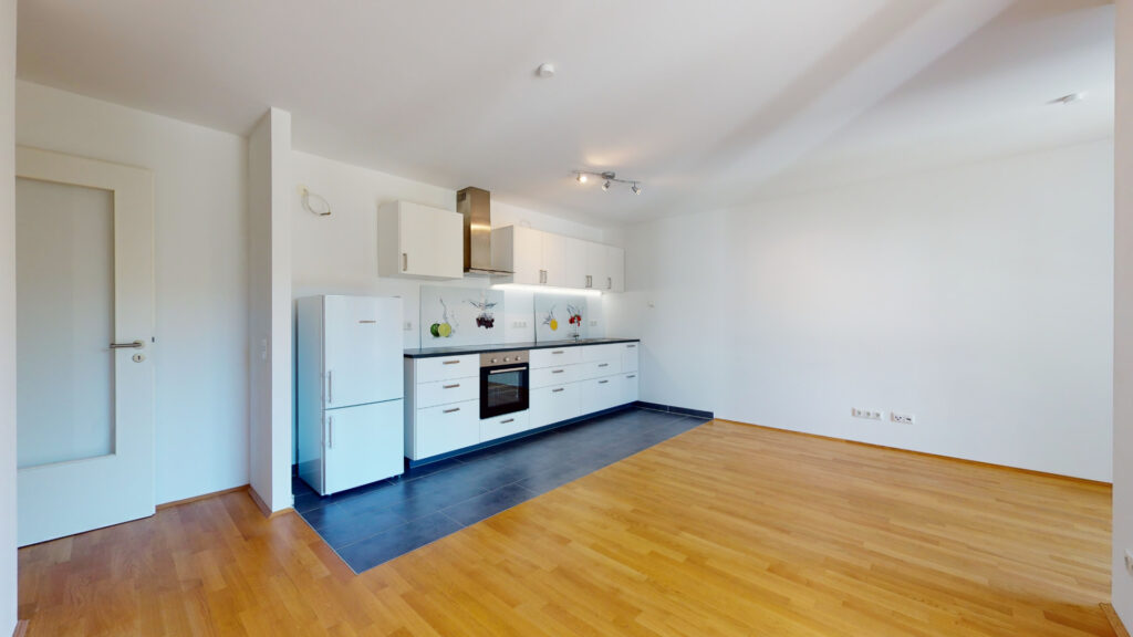 Empty fitted kitchen with white fronts and parquet flooring in a new apartment in Munich-Berg am Laim