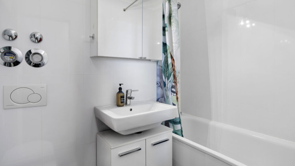 Bathroom with sink, illuminated mirror cabinet and bathtub in an apartment in Munich-Bogenhausen