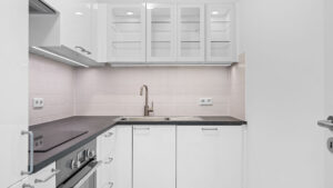 White fitted kitchen with corner unit, wall cabinets, and faucet in Munich Bogenhausen apartment
