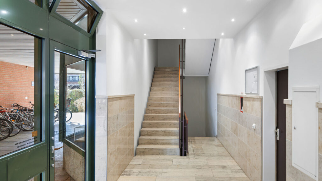 Modern staircase with entrance door and light stone floor in a residential building in Munich-Bogenhausen