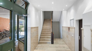 Modernes Treppenhaus mit Eingangstür und hellem Steinboden in einem Wohnhaus in München-Bogenhausen