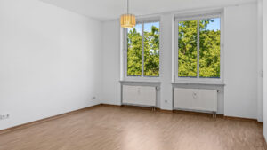 Unfurnished living room with parquet floor, ceiling light, and large window in an apartment in Munich-Bogenhausen