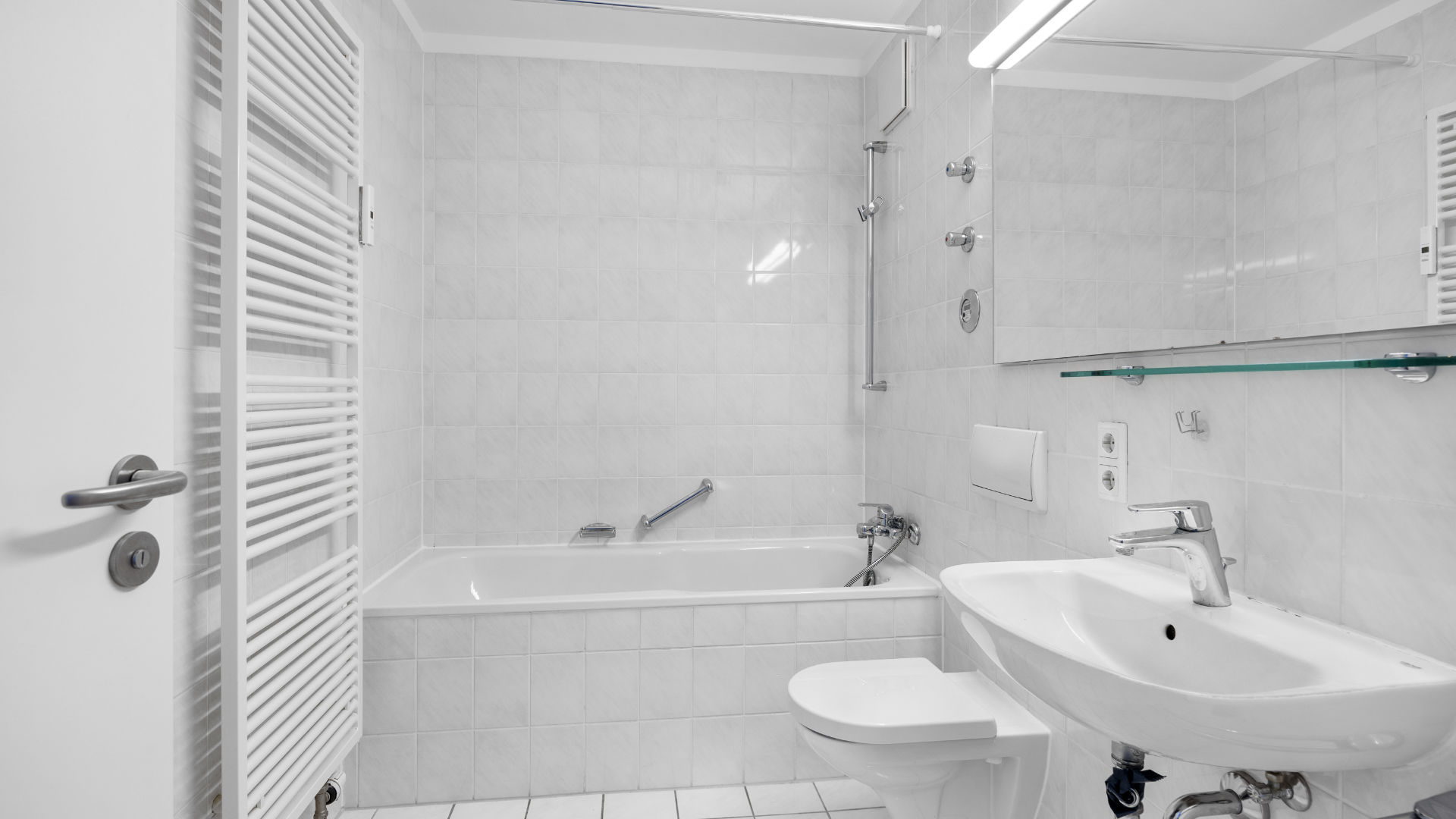 Tiled bathroom with bathtub, toilet and sink in a rented apartment in Munich-Bogenhausen