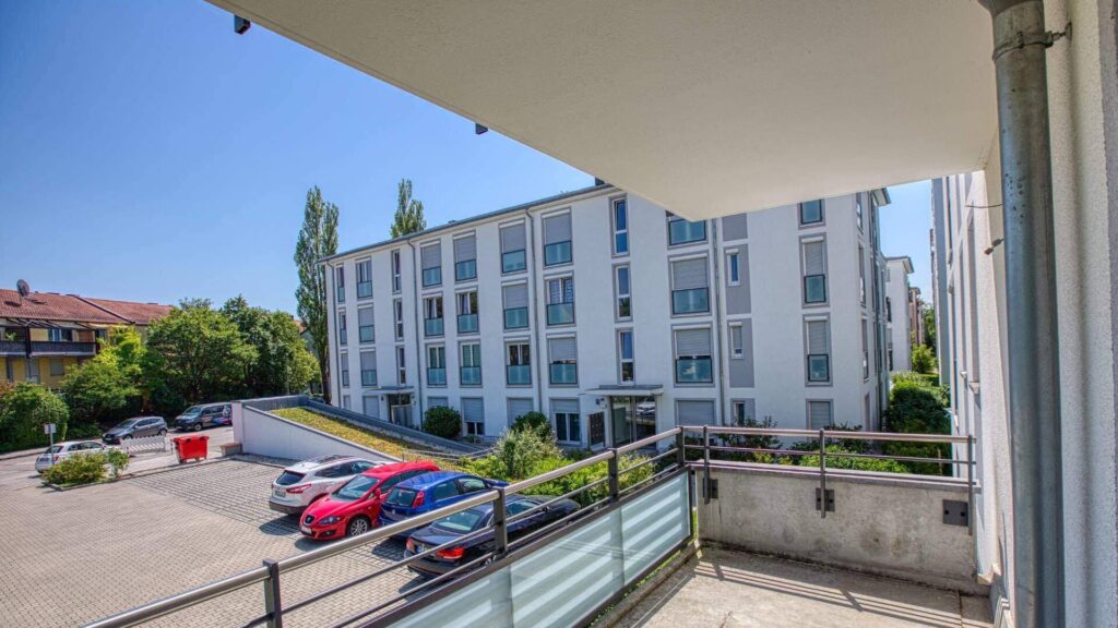 Balkon der Mietwohnung in Bogenhausen mit Blick auf das Nachbargebäude und Parkplatz