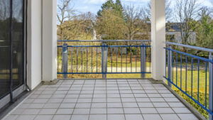 Tiled balcony with a metal railing and a view of the greenery of a rental apartment in Munich-Bogenhausen