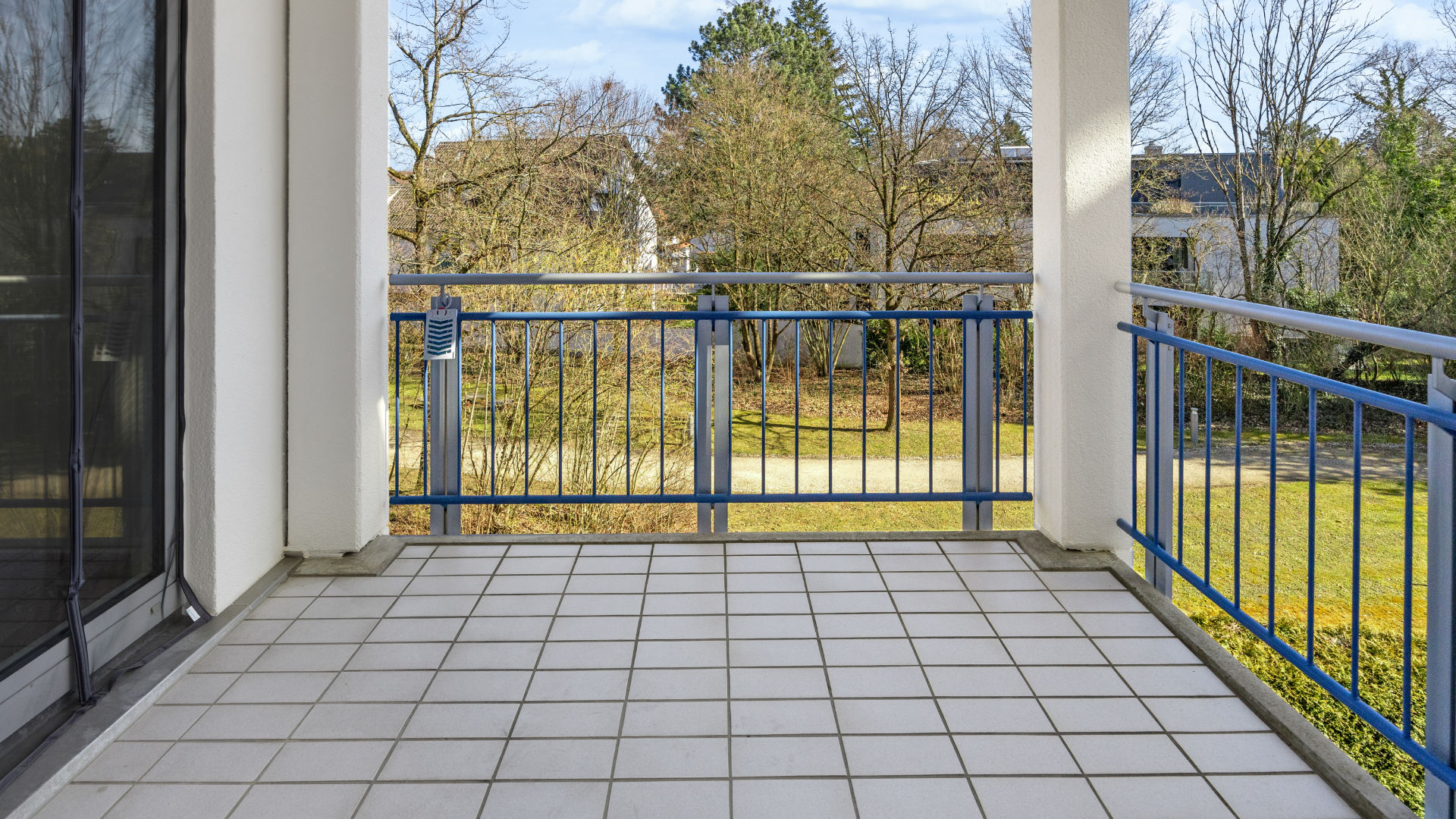 Tiled balcony with a metal railing and a view of the greenery of a rental apartment in Munich-Bogenhausen