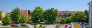Blick aus dem Fenster auf Wohnhäuser, Bäume und eine Parkfläche in Bogenhausen.