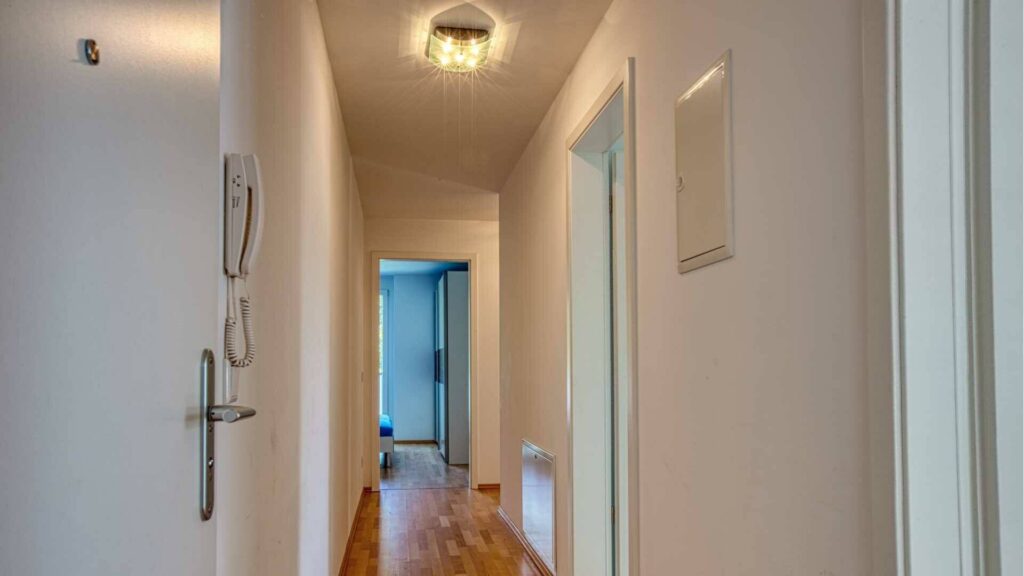 Diele der Mietwohnung in Bogenhausen mit Holzboden, weißen Türen und Blick zum Zimmer