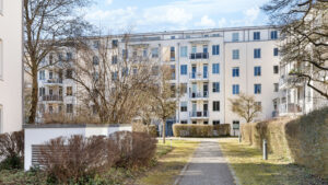 Paved pathway between hedges leading to the multi-story apartment building in Bogenhausen