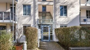 Glazed entrance with canopy and hedges at the apartment building in Bogenhausen