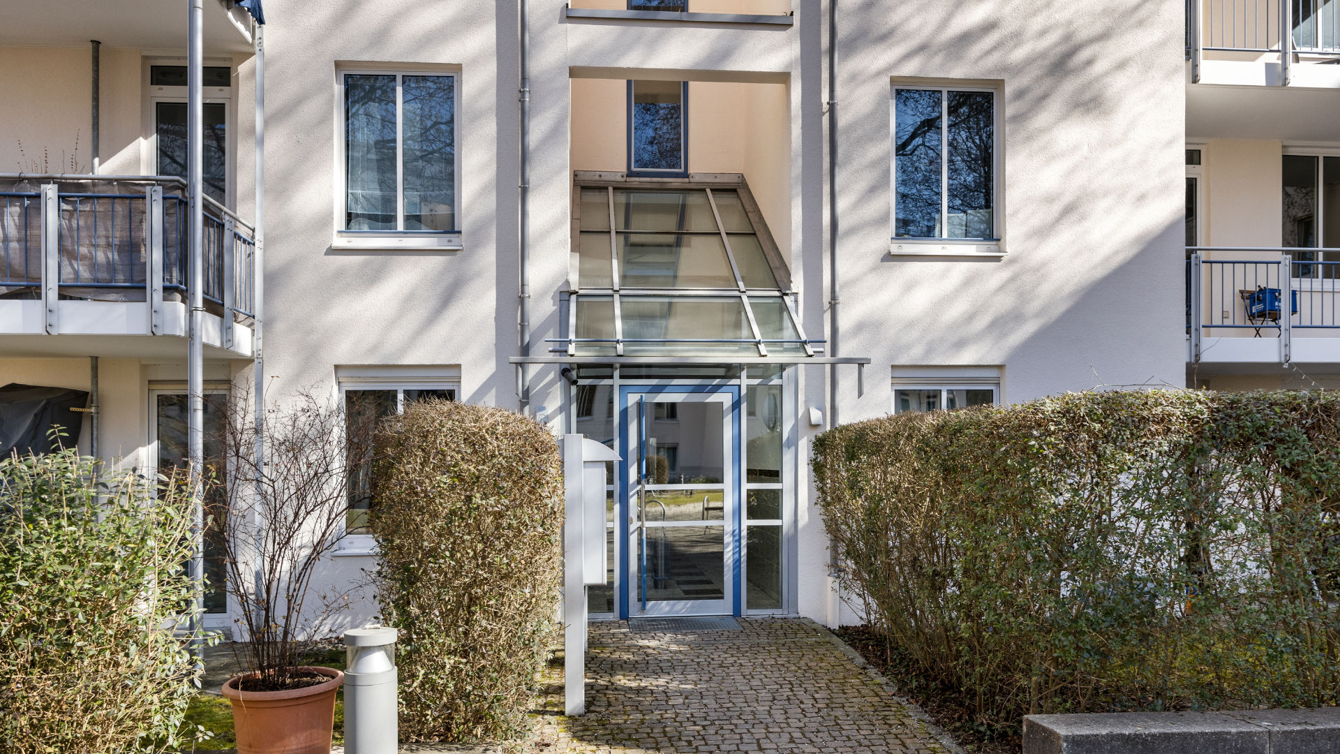 Glazed entrance with canopy and hedges at the apartment building in Bogenhausen