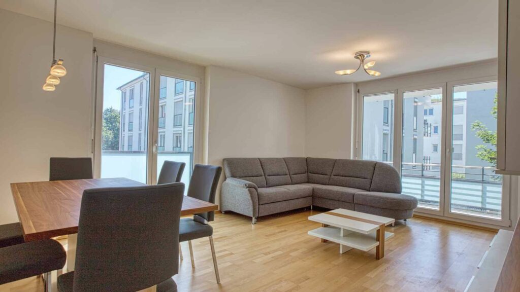 Wohn-Essbereich der Mietwohnung in Bogenhausen mit Sofa, Esstisch und Blick auf Nachbargebäude