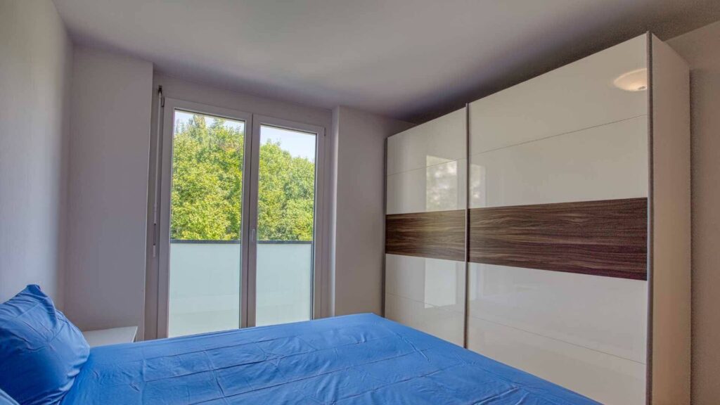 Schlafzimmer der Mietwohnung in Bogenhausen mit Doppelbett, großem Einbauschrank und Balkontür