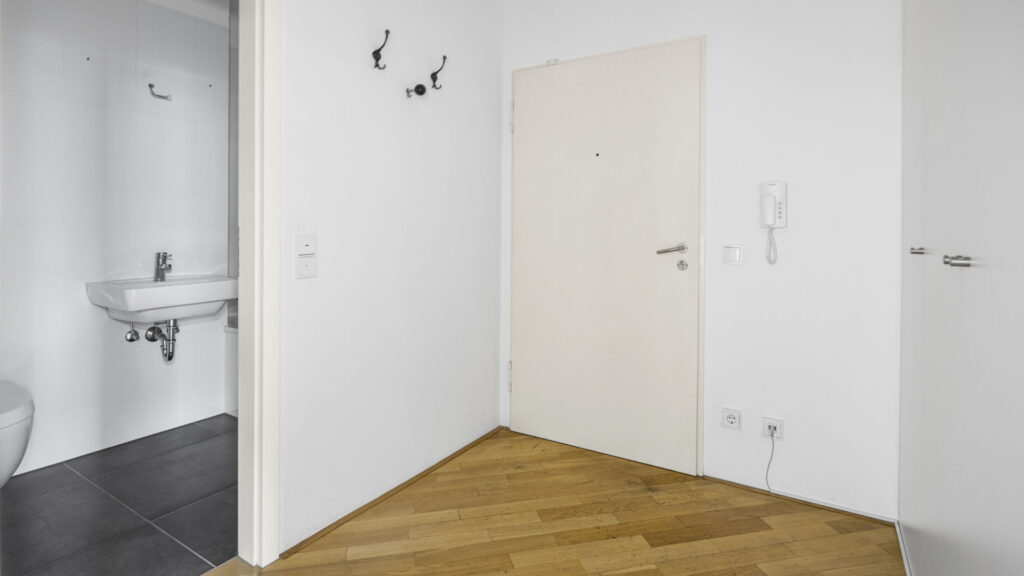 Hallway with a view of a guest toilet and light door in an apartment in Munich-Bogenhausen