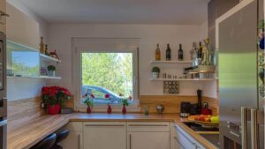 Helle Einbauküche mit Holzarbeitsplatte und Fenster im Haus in München-Feldmoching