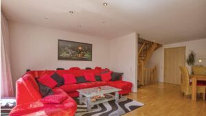 Wohnzimmer mit roter Eckcouch und Parkettboden im Haus in München-Feldmoching