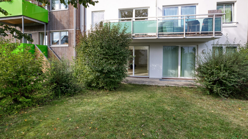 Terrasse mit Rasenfläche und Blick zu den Balkonen des Wohnhauses in München-Forstenried