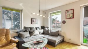 Living room with a gray couch and large windows in an apartment in Munich-Forstenried