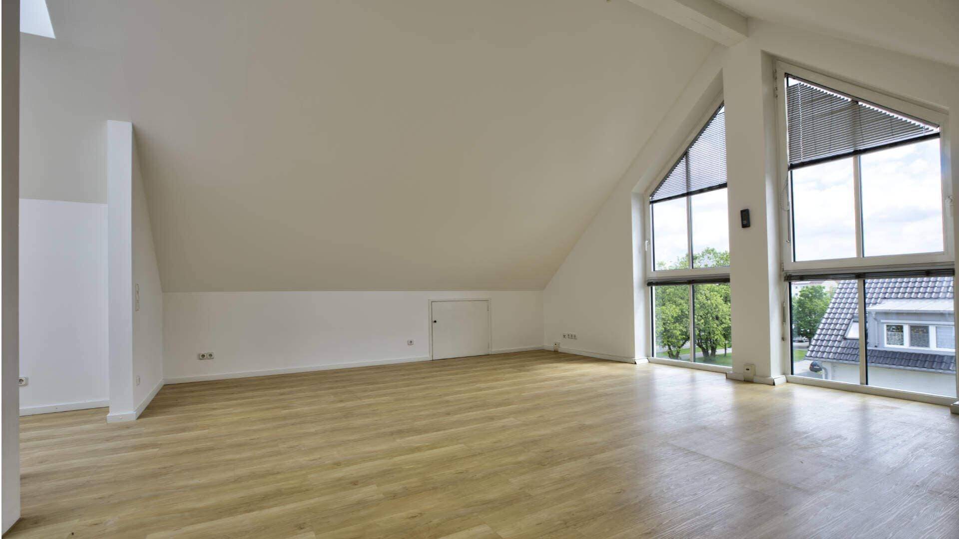 Leerer Dachgeschossraum mit Schrägen und großer Fensterfront in einem Büroobjekt in Fürstenried.