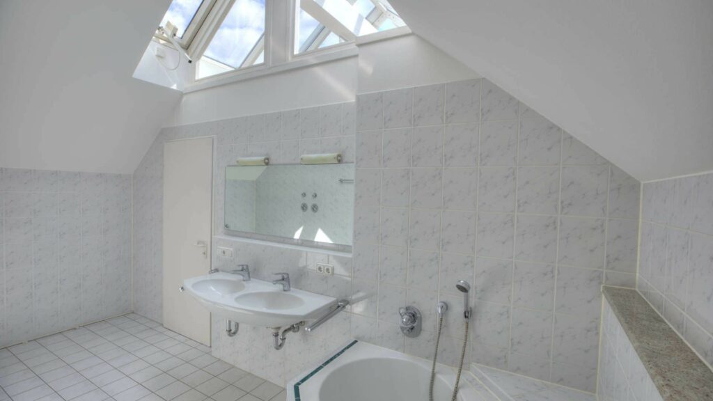 Badezimmer des Bürogebäudes in Fürstenried mit Dachschrägen, Oberlichtern, Waschbecken und Badewanne