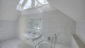 Badezimmer des Bürogebäudes in Fürstenried mit Dachschrägen, Oberlichtern, Waschbecken und Badewanne
