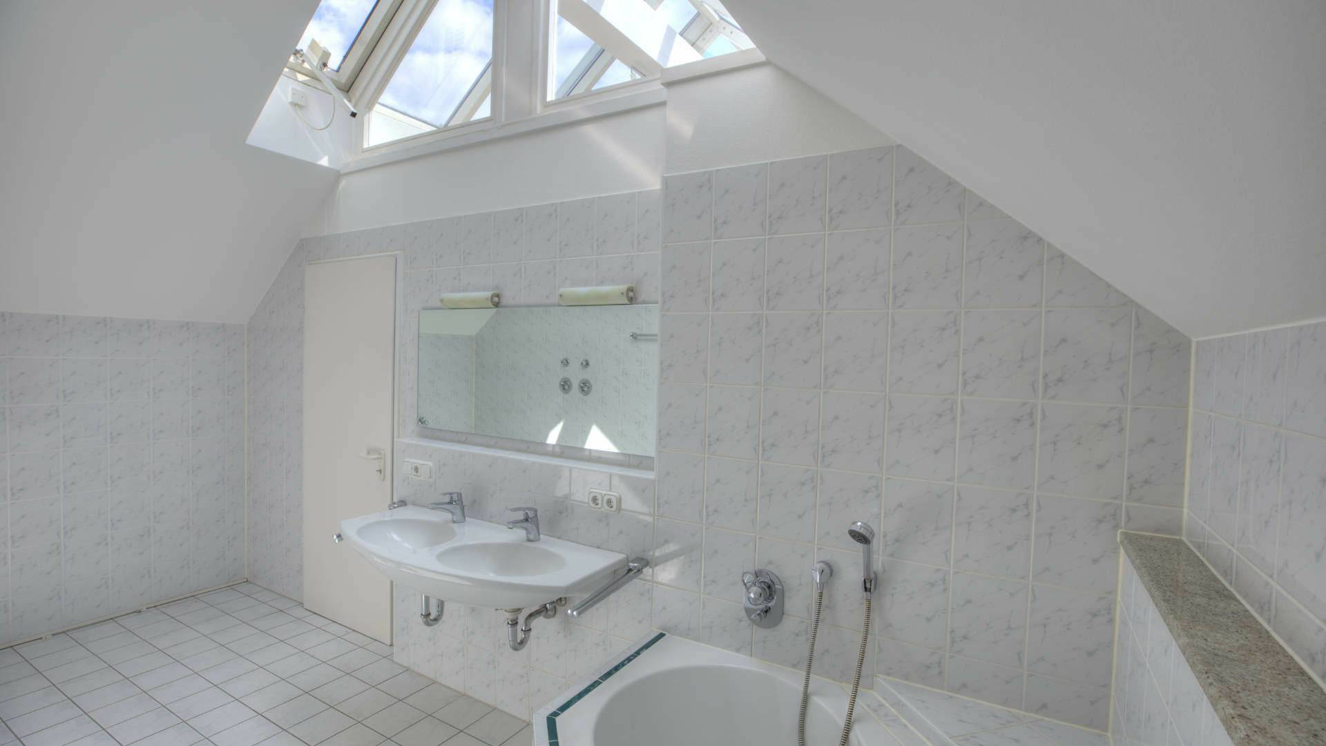Badezimmer des Bürogebäudes in Fürstenried mit Dachschrägen, Oberlichtern, Waschbecken und Badewanne