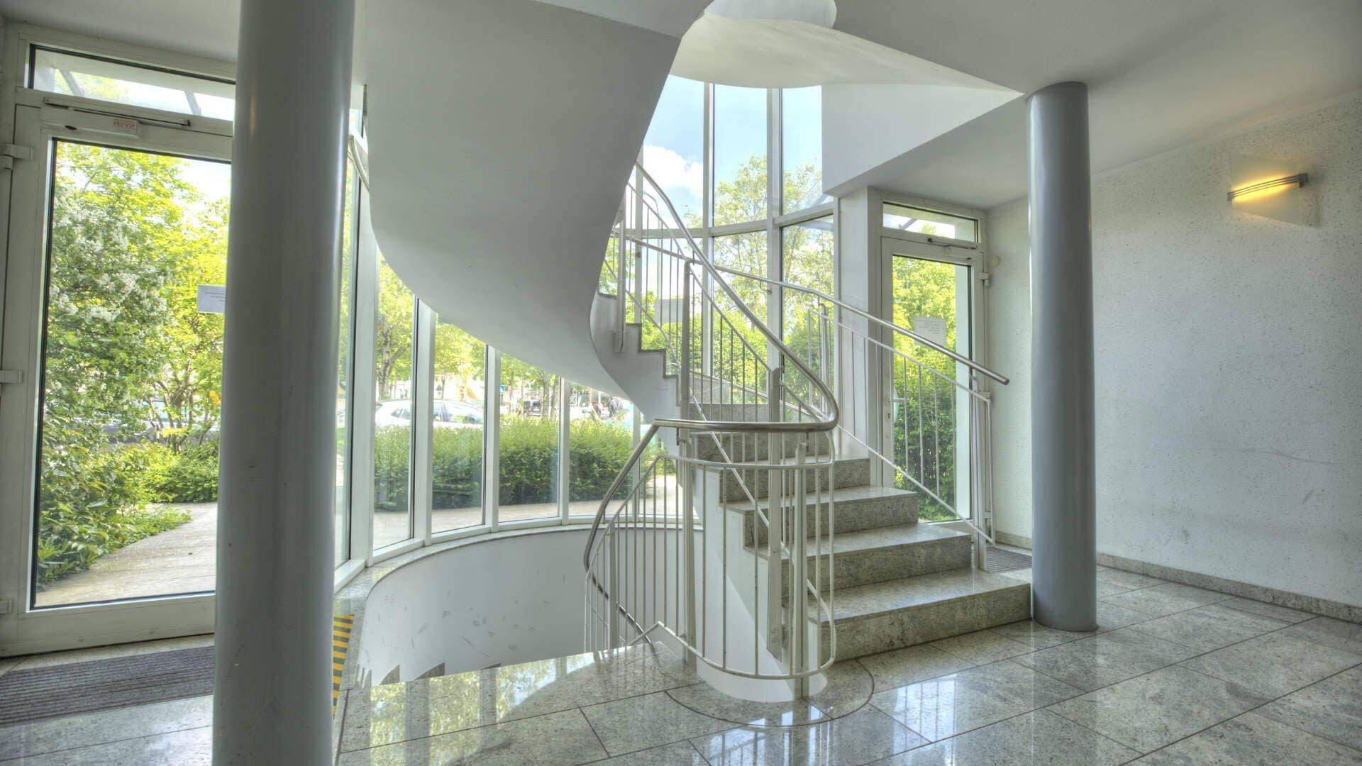 Eingangsbereich des Bürogebäudes in Fürstenried mit weißer Wendeltreppe, Marmorboden und Säulen