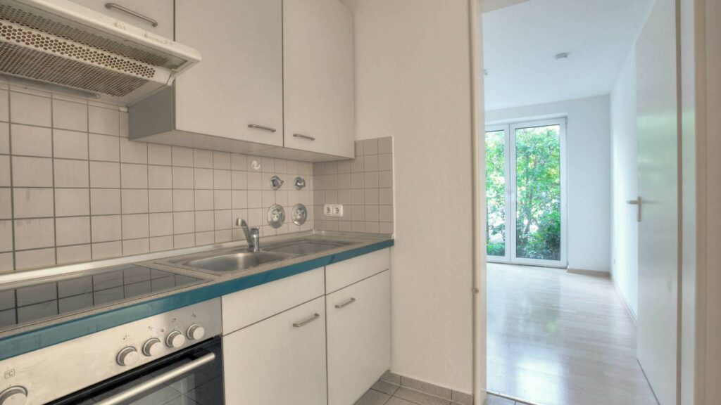 Küche mit weißen Fronten und Blick zum Flur in einer Wohnung in München-Fürstenried