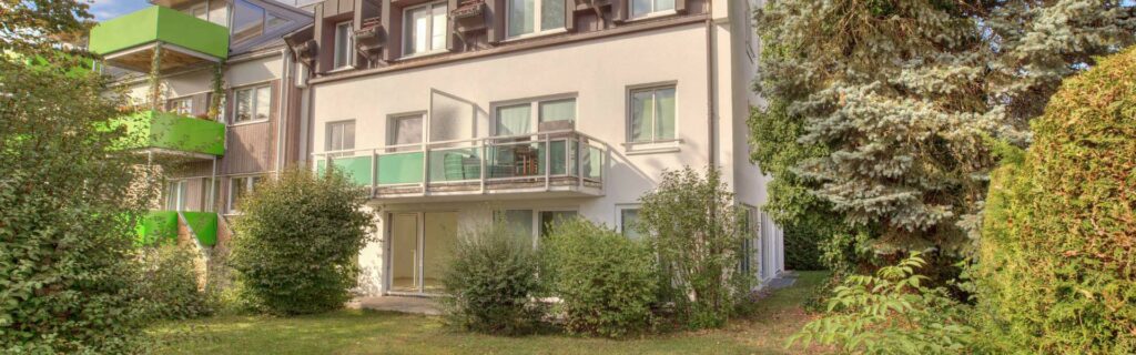 Außenansicht des Wohnhauses mit Balkonen und Grünanlage in München-Fürstenried
