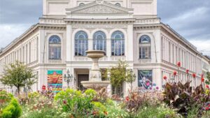 Fassade des Gärtnerplatztheaters mit Brunnen und Blumenbeeten im Gärtnerplatzviertel München