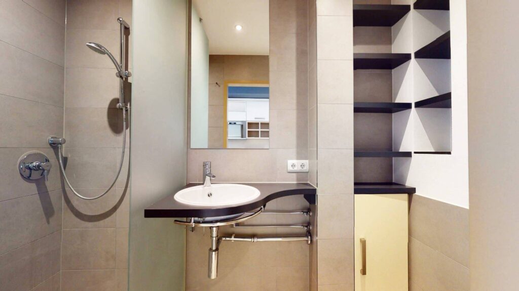 Badezimmer mit Dusche, Waschbecken und Ablagefach einer Wohnung in Garching