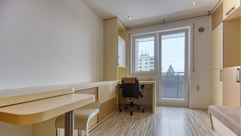 Zimmer mit Schreibtisch und Balkonzugang einer Wohnung in Garching bei München