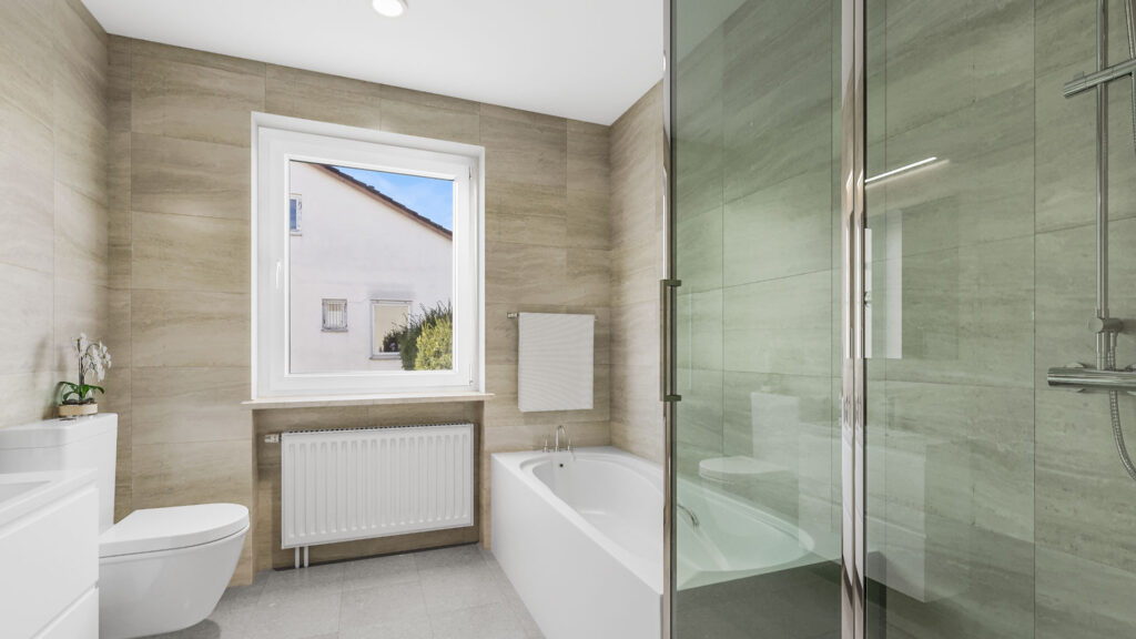 Badezimmer mit Badewanne, WC und Glasdusche in einem Haus zum Kauf in Gauting