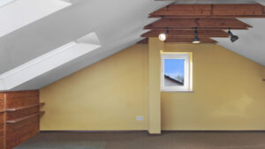 Dachschräge mit Dachfenster und gelben Wänden im unrenovierten Dachstudio in Gauting