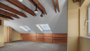 Dachgeschossraum mit Holzbalken, Dachfenstern und Einbauschränken in Gauting