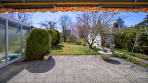 Gepflasterte Terrasse mit Markise und kleinem Springbrunnen im Garten eines Hauses in Gauting
