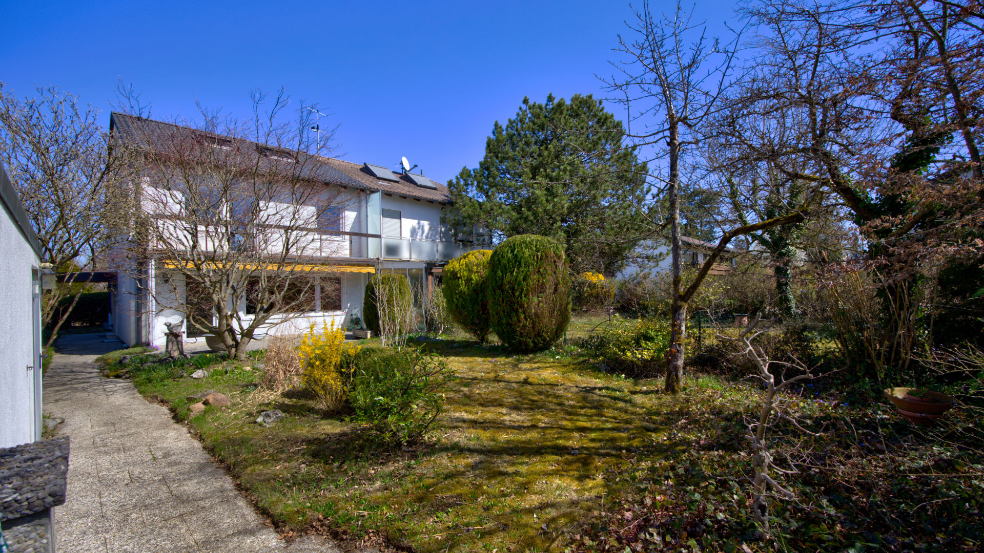Hausansicht mit Garten und Bäumen eines Einfamilienhauses in Gauting