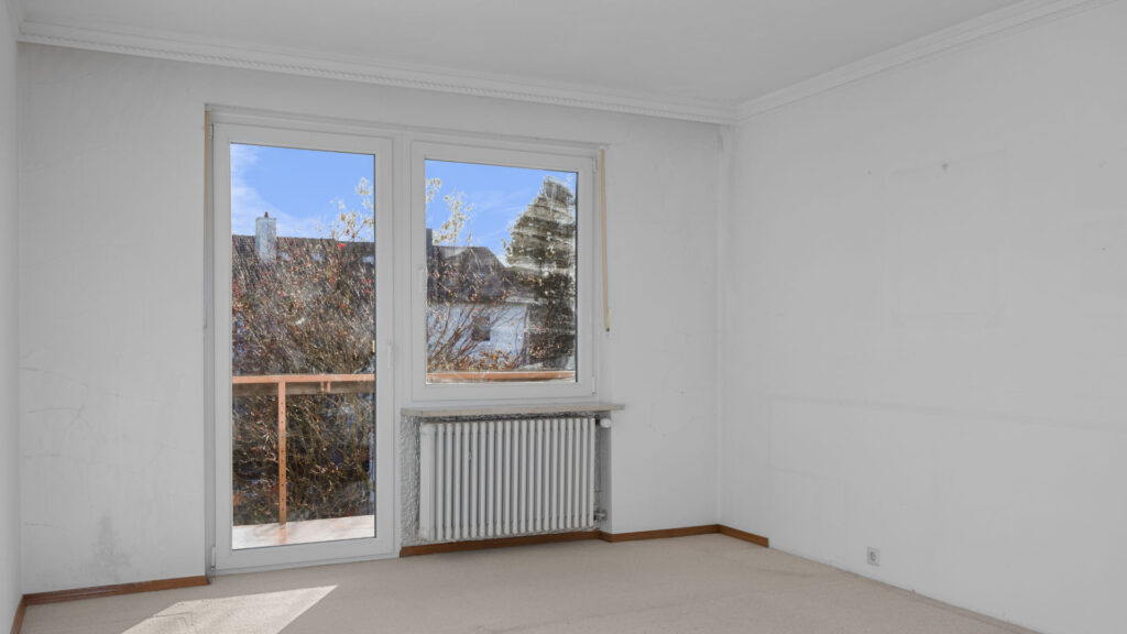 Leeres Schlafzimmer mit Terrassentür zum Balkon und Ausblick auf Bäume in Gauting