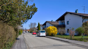 Ruhige Wohnstraße mit Einfamilienhäusern und blühendem Strauch in der Nachbarschaft des Hauses in Gauting
