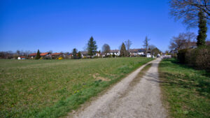 Feldweg durch grüne Wiesen mit Blick auf die Ortschaft Gauting in der Umgebung dieses Hauses von Rogers Immobilien