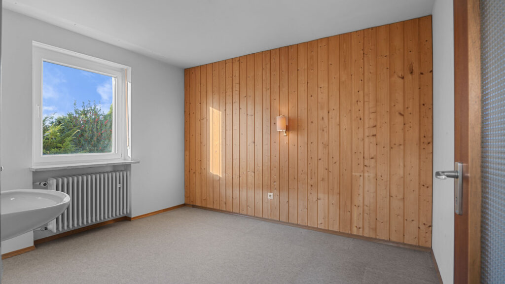 Leeres Zimmer mit Holzvertäfelung an der Wand und Teppichboden im Originalzustand, Gauting