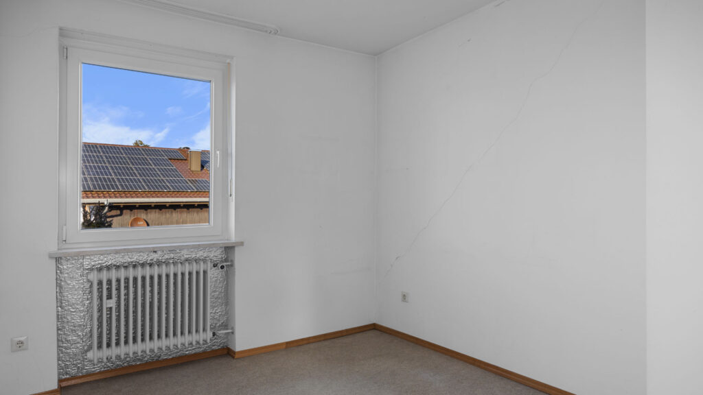 Leeres Zimmer mit hellen Wänden und Teppichboden, Fensterausblick auf Dächer, Gauting