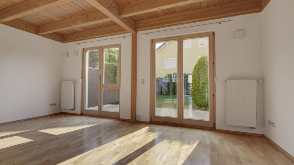 Light-filled living space with exposed wooden beam ceiling and patio doors in an apartment building in Germering