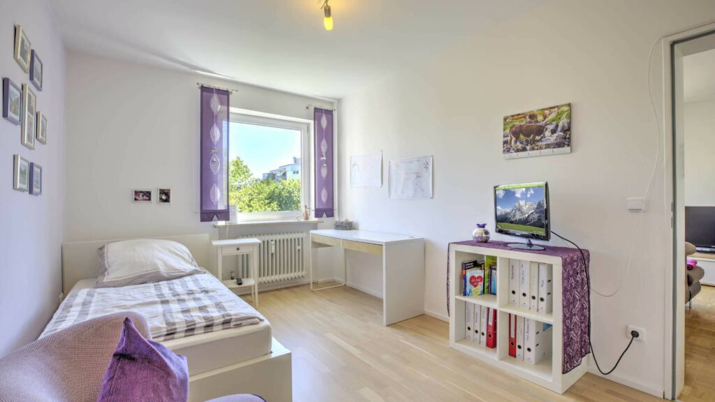 Kleines Zimmer mit Bett, Schreibtisch und Regal in einer Wohnung in Germering