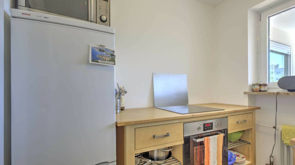 Kompakte Küchenzeile mit Kühlschrank und Fenster in einer Wohnung in Germering