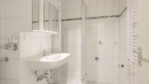Älteres Badezimmer mit weißem Waschbecken, Fliesen und Handtuchheizkörper in einer Wohnung in München-Giesing