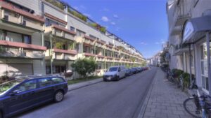 Straßenzug mit Altbau-Häuserzeile, Balkonen und geparkten Autos im Stadtteil Giesing in München