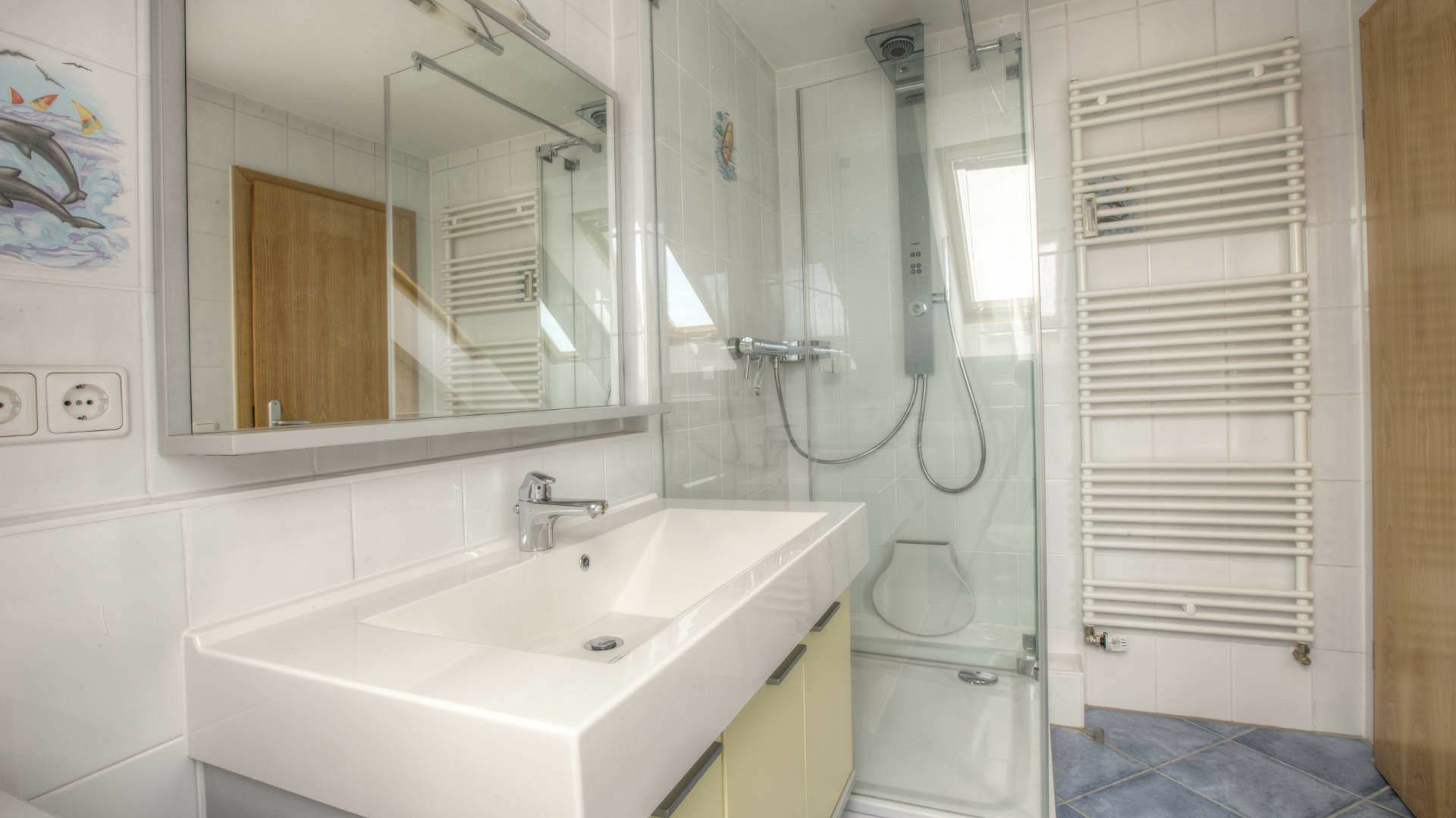 Badezimmer mit Dusche, Waschbecken und Handtuchheizkörper in einer Wohnung in Gilching